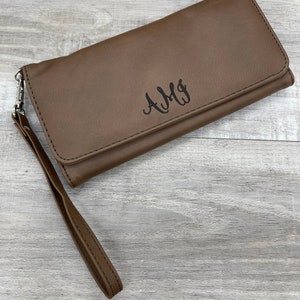May include: A brown leather wallet with a wrist strap and the monogram "AMY" embossed on the front.