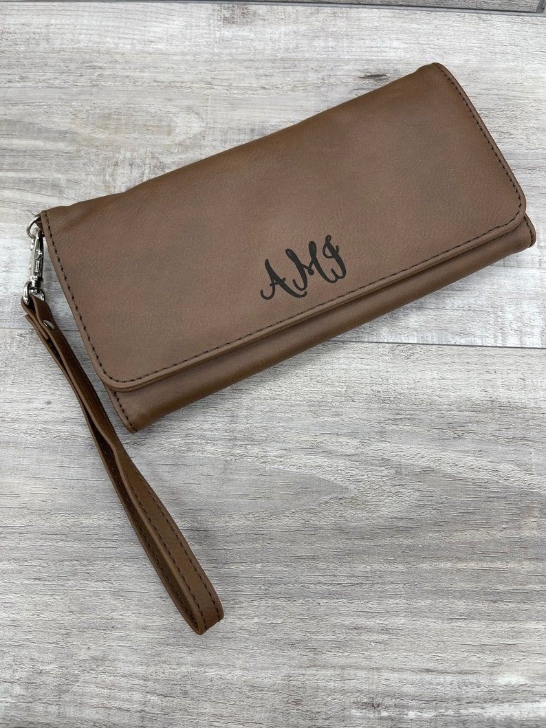 May include: A brown leather wallet with a wrist strap and the monogram "AMY" embossed on the front.