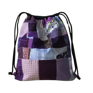 Könnte beinhalten: Lila und lavendelfarbener Patchwork-Kordelzugbeutel mit schwarzem Kordelzug.