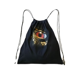 Peut inclure: Sac à cordon noir avec un imprimé graphique d'un œil rouge. L'œil est entouré d'écailles dorées et noires.