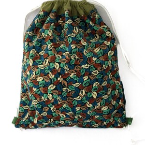 May include: A green drawstring bag with a leaf print pattern in shades of blue, green, brown, and cream. The bag is made of a soft, textured fabric.