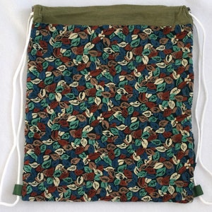 May include: A green drawstring bag with a white cord and a floral print featuring brown, blue, and green leaves.