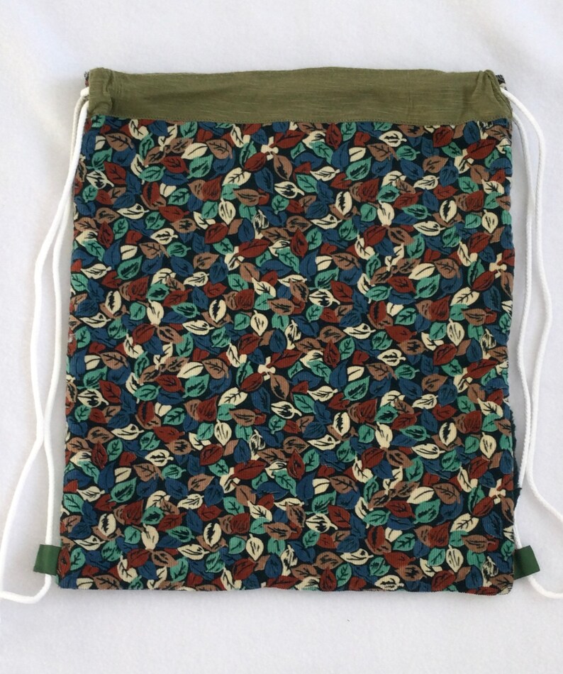 May include: A green drawstring bag with a white cord and a floral print featuring brown, blue, and green leaves.