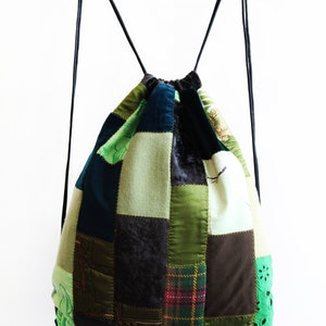 May include: A green, brown and black patchwork drawstring backpack with black drawstrings.
