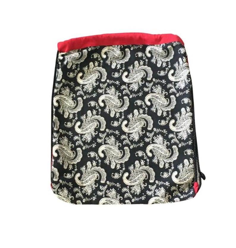 以下が含まれることがあります： 白のペイズリー柄と上部に赤いトリムが付いた黒い巾着袋