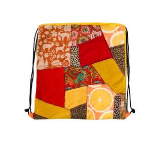 May include: A yellow drawstring bag with a patchwork design. The bag is made of different fabrics with various patterns, including floral, geometric, and animal prints. The bag has a red, orange, yellow, and brown color scheme.