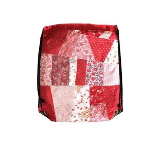 以下が含まれることがあります： 赤色の巾着袋で、パッチワークのデザインが施されています。様々な赤と白のフローラルパターンが特徴です。