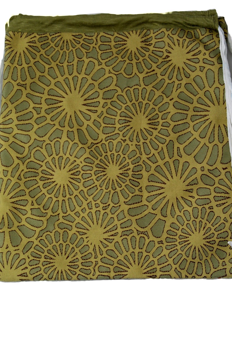 Op de afbeelding: Een groene trekkoordtas met een herhalend patroon van bruine, ronde ontwerpen.