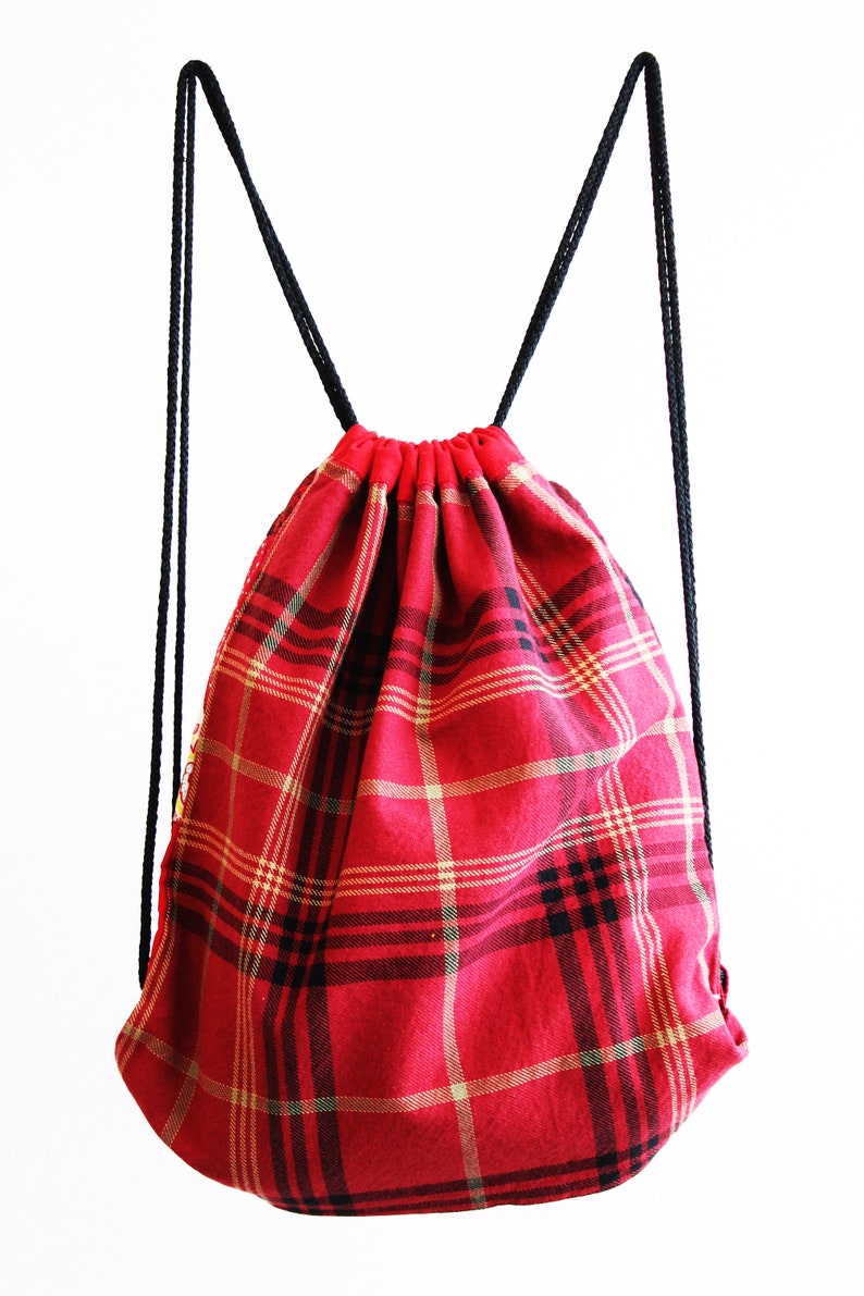 May include: Red and black plaid drawstring backpack with black drawstrings.