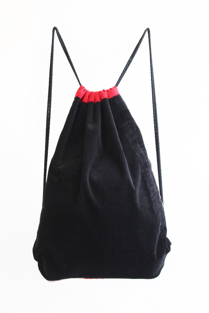 May include: Black drawstring bag with red trim. The bag is made of a soft, velvety material.