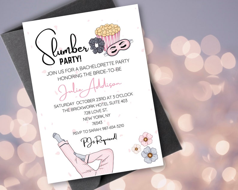 May include: A white invitation card with pink and black illustrations. The text on the card reads "Slumber Party!" and includes details for a bachelorette party for Julie Addison. The party is scheduled for Saturday, October 23rd at 3 o'clock at The Brickwork Hotel, Suite 403, 728 Love St., New York, NY 76543. The RSVP information is provided with a phone number and the text "PJs Required!"