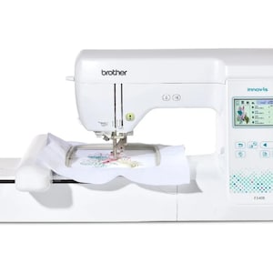 May include: A white Brother Innovis F540E embroidery machine. The machine has a digital display screen, control buttons, and a needle with fabric in the embroidery hoop. It is designed for sewing and embroidery projects.