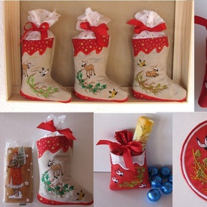 Puede incluir: Cinco calcetines de Navidad rojos y blancos con diseños bordados de ciervos, pájaros y acebo. Los calcetines están llenos de pequeños regalos y se muestran en una caja de madera.