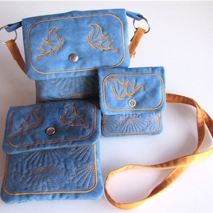 May include: Three blue fabric bags with gold embroidery of butterflies. The bags have adjustable straps and are different sizes.