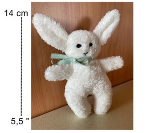 May include: White plush bunny rabbit toy with a light green bow. The toy is 5.5 inches tall and 14 cm long.