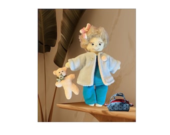 May include: A handmade doll wearing a light blue jacket and turquoise pants holds a small teddy bear. The doll has blonde hair and a pink bow. The doll is standing on a wooden shelf with a blue and white polka dot handbag.