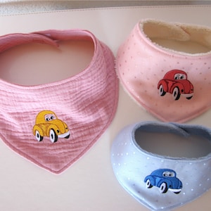 May include: Three baby bibs in pink, blue and white with embroidered cars. The cars are yellow, red and blue.