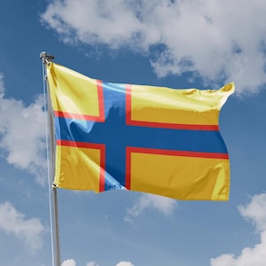 Könnte beinhalten: Eine gelbe Flagge mit einem blauen und roten Kreuz, die im Wind weht vor einem blauen Himmel mit weißen Wolken.