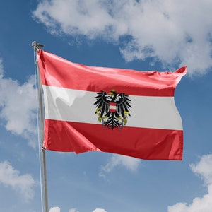 May include: A red, white, and red Austrian flag with the Austrian coat of arms in the center, waving in the wind against a blue sky with white clouds.