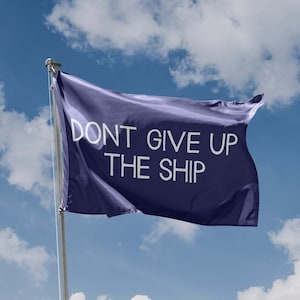 Könnte beinhalten: Eine blaue Flagge mit dem Text "DON'T GIVE UP THE SHIP" in weißen Buchstaben vor einem blauen Himmel mit weißen Wolken.