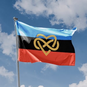 May include: A blue, black, and red flag with a gold heart-shaped knot symbol. The flag is waving in the wind against a blue sky with white clouds.