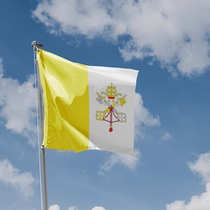 Może przedstawiać: Żółto-biała flaga z herbem przedstawiającym klucze i koronę. Flaga powiewa na wietrze na tle błękitnego nieba z białymi chmurami.