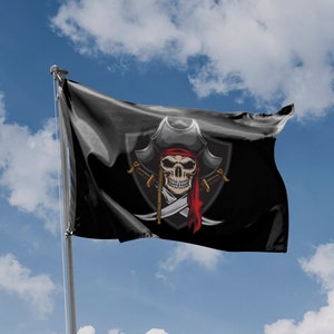 Puede incluir: Una bandera pirata negra con un diseño de calavera y huesos cruzados blancos. La calavera lleva un pañuelo negro y rojo y un sombrero de pirata negro. La bandera ondea al viento contra un cielo azul con nubes blancas.
