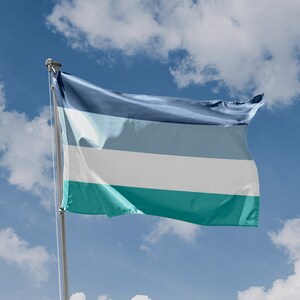 May include: A blue, gray, white, and teal flag waving in the wind against a blue sky with white clouds.