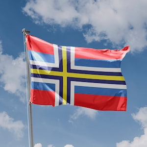 Könnte beinhalten: Eine rot-weiß-blaue Flagge mit einem gelben Kreuz und einem blauen Kreuz auf weißem Hintergrund. Die Flagge weht im Wind vor einem blauen Himmel mit weißen Wolken.