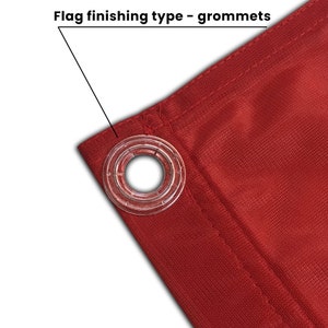 May include: Close-up of a red fabric flag with a clear plastic grommet. The grommet is reinforced with a metal ring.  "Flag finishing type - grommets" is written above the grommet.