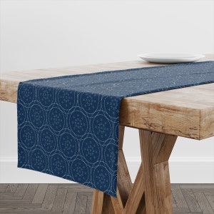 Peut inclure: Un chemin de table bleu marine avec un motif géométrique blanc. Le chemin de table est sur une table en bois avec une assiette blanche sur la table.