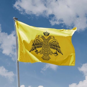 May include: A yellow flag featuring a black double-headed eagle with a crown above it. The eagle is holding a sword and a sceptre.
