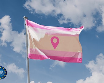 May include: A pink, white, and beige flag with a pink location pin symbol in the center. The flag is flying on a flagpole against a blue sky with white clouds.