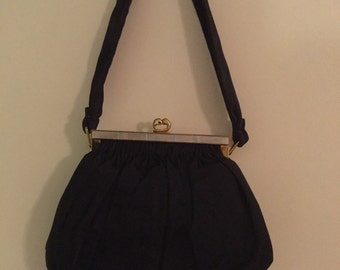 May include: A black fabric purse with a gold clasp and a long black strap.