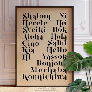 Peut inclure: Une affiche murale de style vintage encadrée avec des mots tels que "Shalom" et "Aloha" en noir sur fond beige. L'affiche comprend également le texte "ANTHI LEONI DECOR VINTAGE STYLE WALL ART & TYPOGRAPHY."
