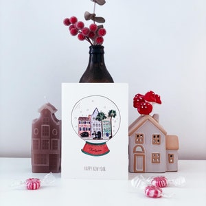 Carte de voeux "Happy New Year" avec le mythique Rainbow Row de Charleston dans une boule à neige