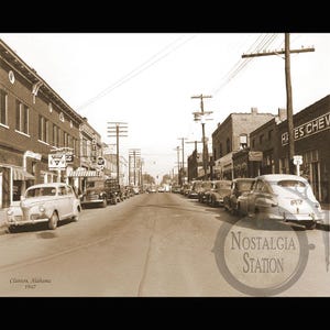 May include: Sepia-toned photograph of a street scene in Clanton, Alabama, from 1947. Classic cars are parked along the street, with buildings and storefronts lining both sides. The image has a vintage aesthetic.