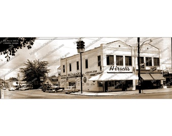 May include: A black and white photo of a street corner in Columbus, Georgia. The photo shows three storefronts, one of which is a jewelry store called "Hirschs".