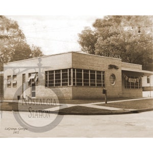 May include: A black and white photo of a brick building with the word "Greyhound" above the entrance. The building has large windows and a sign that says "LaGrange, Georgia 1952".