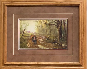 Könnte beinhalten: Ein gerahmter Druck eines Gemäldes, das eine Gruppe wilder Truthähne in einer Waldlandschaft zeigt. Die Truthähne gehen auf einem Feldweg entlang, im Hintergrund ist eine rote Scheune zu sehen. Das Gemälde ist vor dem Hintergrund grüner Bäume und eines blauen Himmels gemalt.