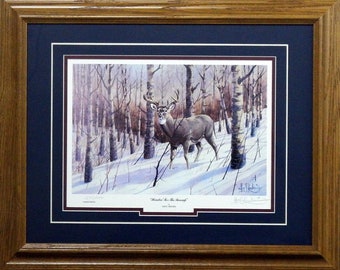 Könnte beinhalten: Ein gerahmter Druck eines Weißwedelhirsches in einem schneebedeckten Wald. Das Reh schaut direkt auf den Betrachter. Der Druck trägt den Titel "Wanderer In The Snow" von Fred Bacher.