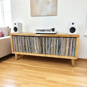 May include: A wooden record player stand with a turntable and two speakers. The stand has shelves filled with vinyl records.