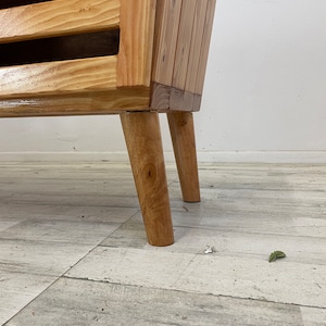 May include: A wooden shelf unit with four shelves and four legs. The shelf unit is made of natural wood and has a light brown finish.