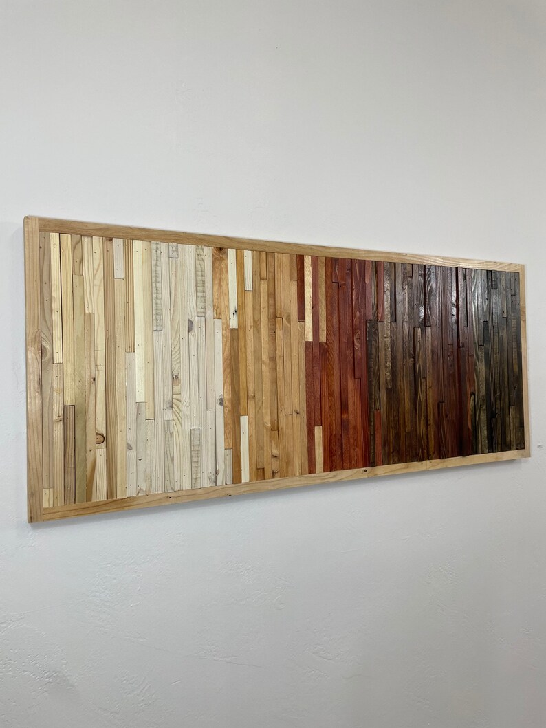 May include: A rectangular wall art piece made of wood planks in various shades of brown, beige, and white. The planks are arranged in a horizontal pattern, creating a gradient effect from light to dark.
