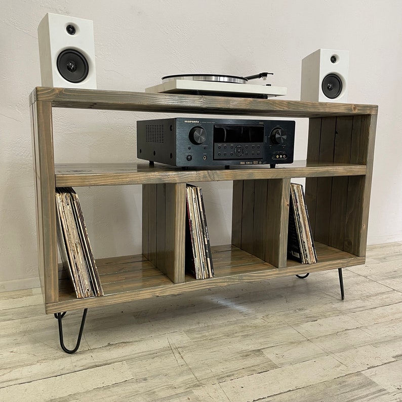 May include: A wooden record player stand with four shelves, two speakers, a record player, and a stereo receiver. The stand has hairpin legs and is made of a dark wood.