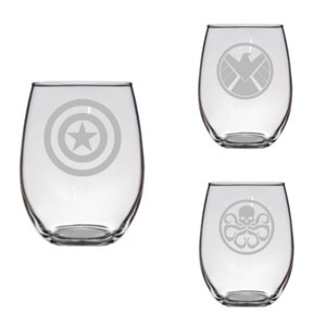 Puede incluir: Tres copas de vino sin tallo transparentes con diseños grabados. Una copa presenta un diseño de estrella en círculo, otra tiene un escudo con alas y la tercera un diseño de calavera de pulpo.