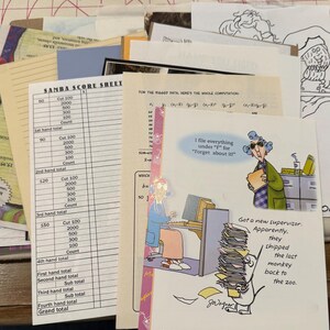 May include: A collection of various papers and documents, including a "SAMBA SCORE SHEET" and a cartoon illustration with the text "I file everything under 'F' for 'Forget about it!'". The image features a mix of printed materials.