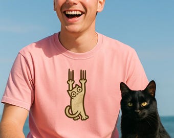 May include: A pink t-shirt with a cat graphic is worn by a person with pink hair. A black cat sits next to the person. The background is a blue sky and ocean.