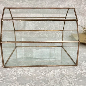 May include: A glass display case with a gold frame. The case has two shelves and a clear glass top.