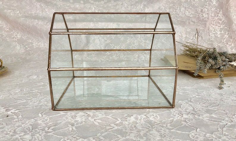 May include: A glass display case with a gold frame. The case has two shelves and a clear glass top.